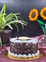 Whole Black Forest cake decorated with chocolate shavings, fresh cherries, and whipped cream