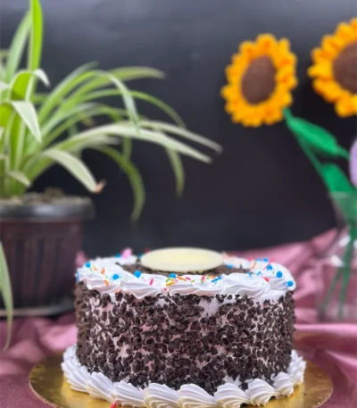 Whole Black Forest cake decorated with chocolate shavings, fresh cherries, and whipped cream