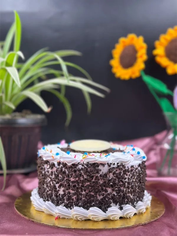 Whole Black Forest cake decorated with chocolate shavings, fresh cherries, and whipped cream