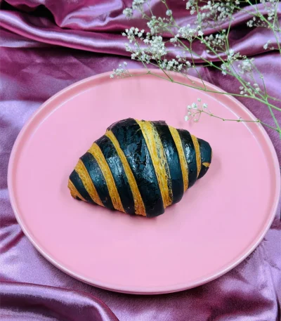 Chocolate Croissant - Golden croissant with chocolate drizzle on pink plate