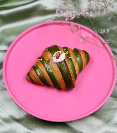 Pistachio croissant topped with fresh cherry and rich cream