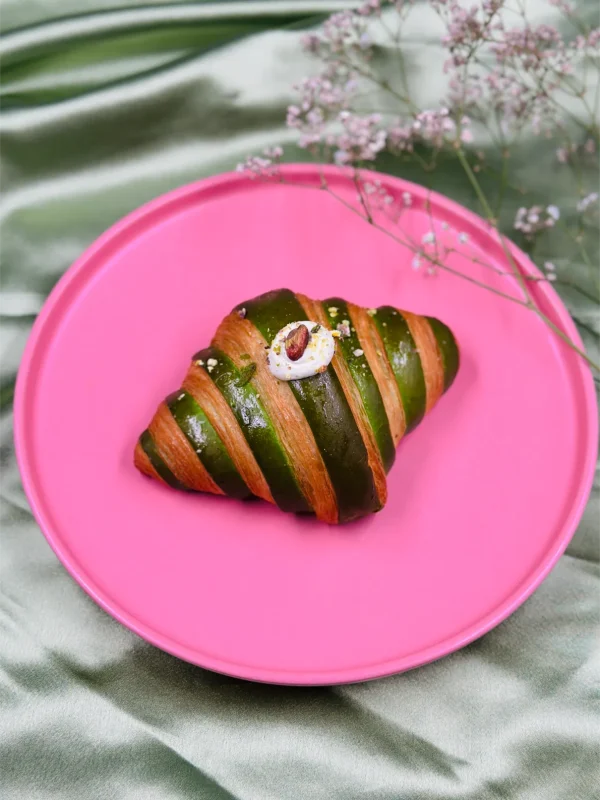Pistachio croissant topped with fresh cherry and rich cream