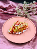 Golden baked croissant with strawberry garnish and powdered sugar